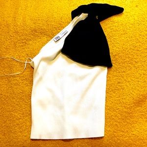 One shoulder white sweater with big black bow that hangs over the other shoulder
